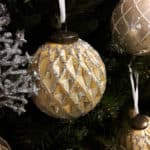 Goldene Christbaumkugeln mit speziellen Ornamenten und glitzernden Applikationen.